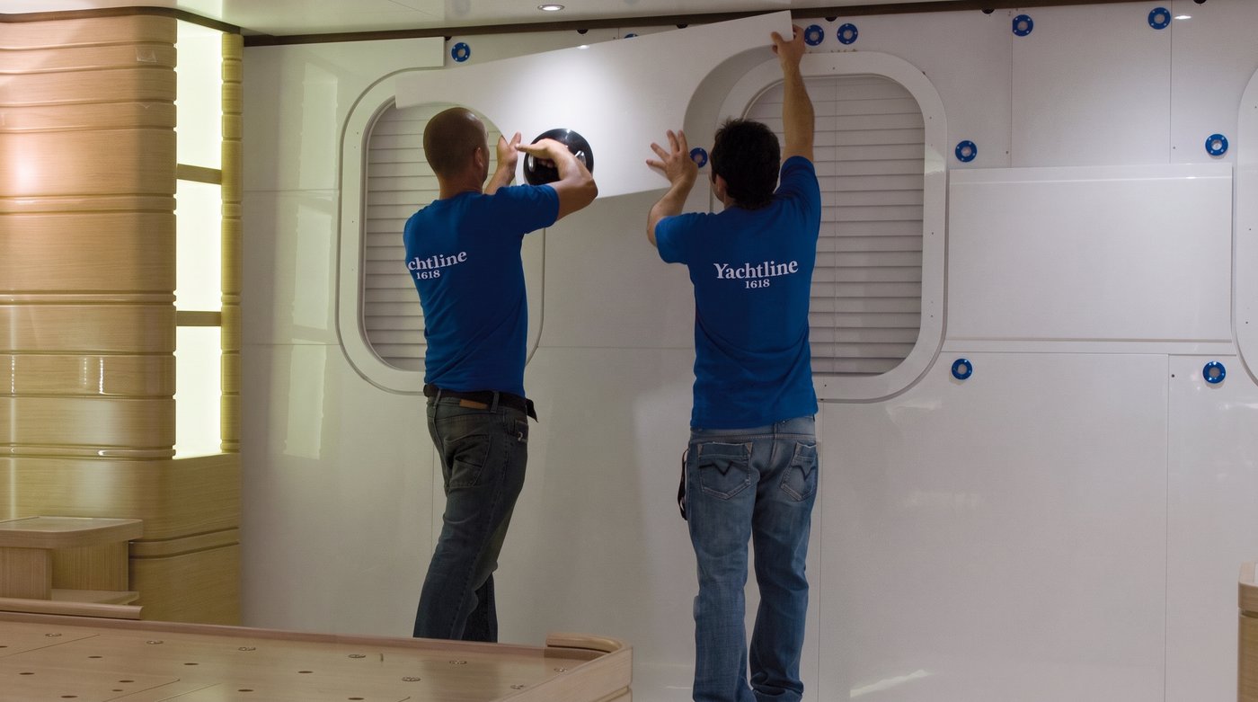 Two fitters mounting a white panel with FITLOCK systems inside a yacht